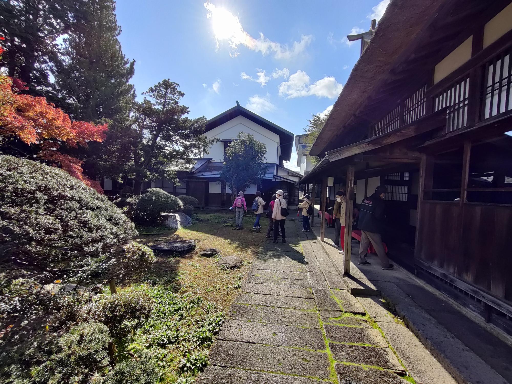 左側には紅葉で色づいたきれいな庭があり、参加者の方々が見学をしている丸大扇屋での様子の写真
