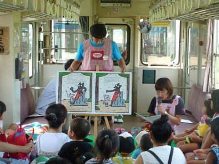 車内で子供達に読み聞かせのイベントを行っている写真