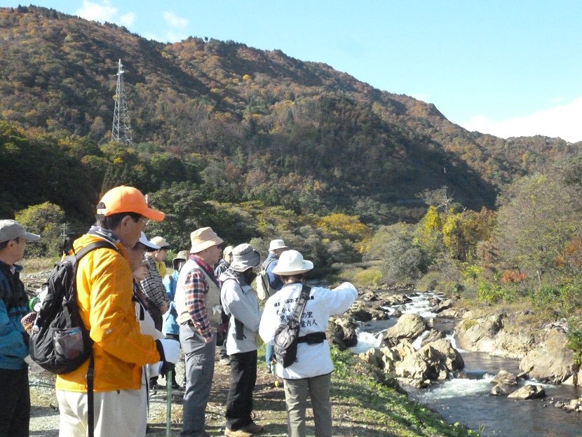 参加者の方々がガイドさんの説明を聞きながら石渕渓谷を川岸から見ている様子の写真